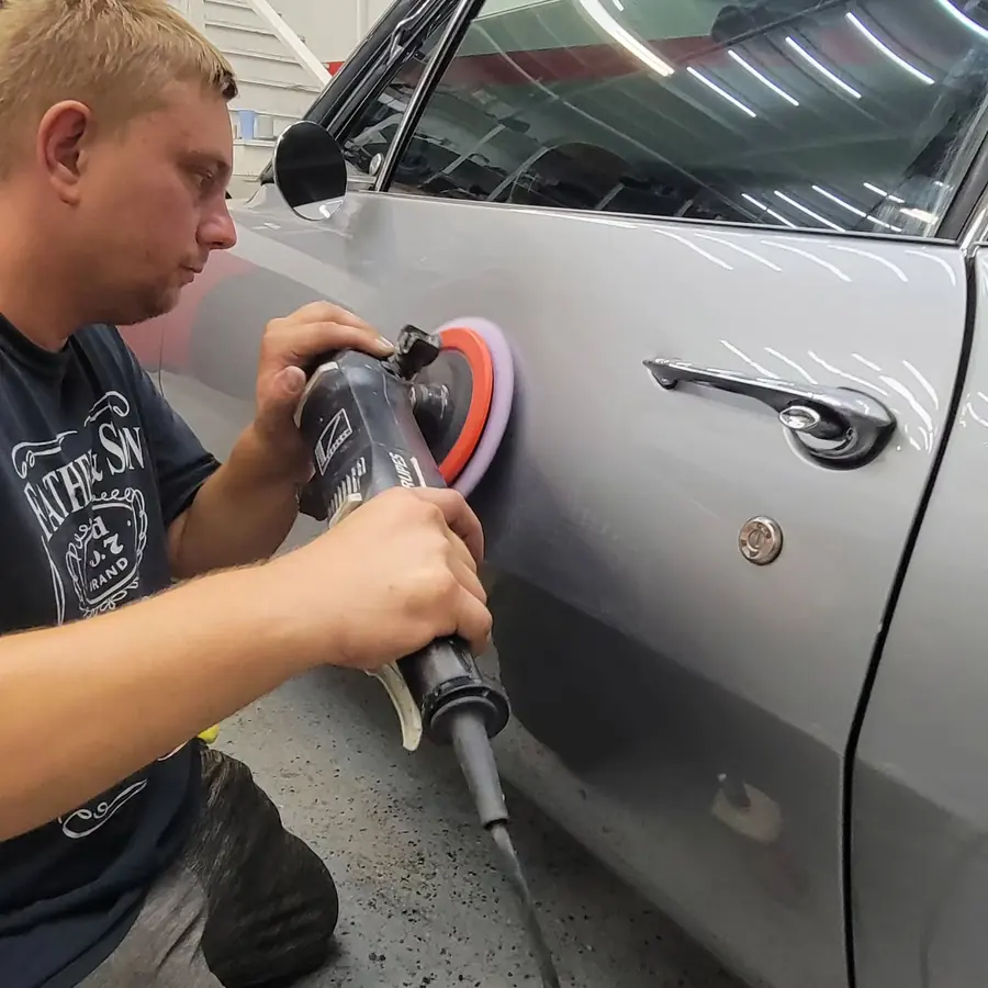 Alex machine-polishing the door of a silver car