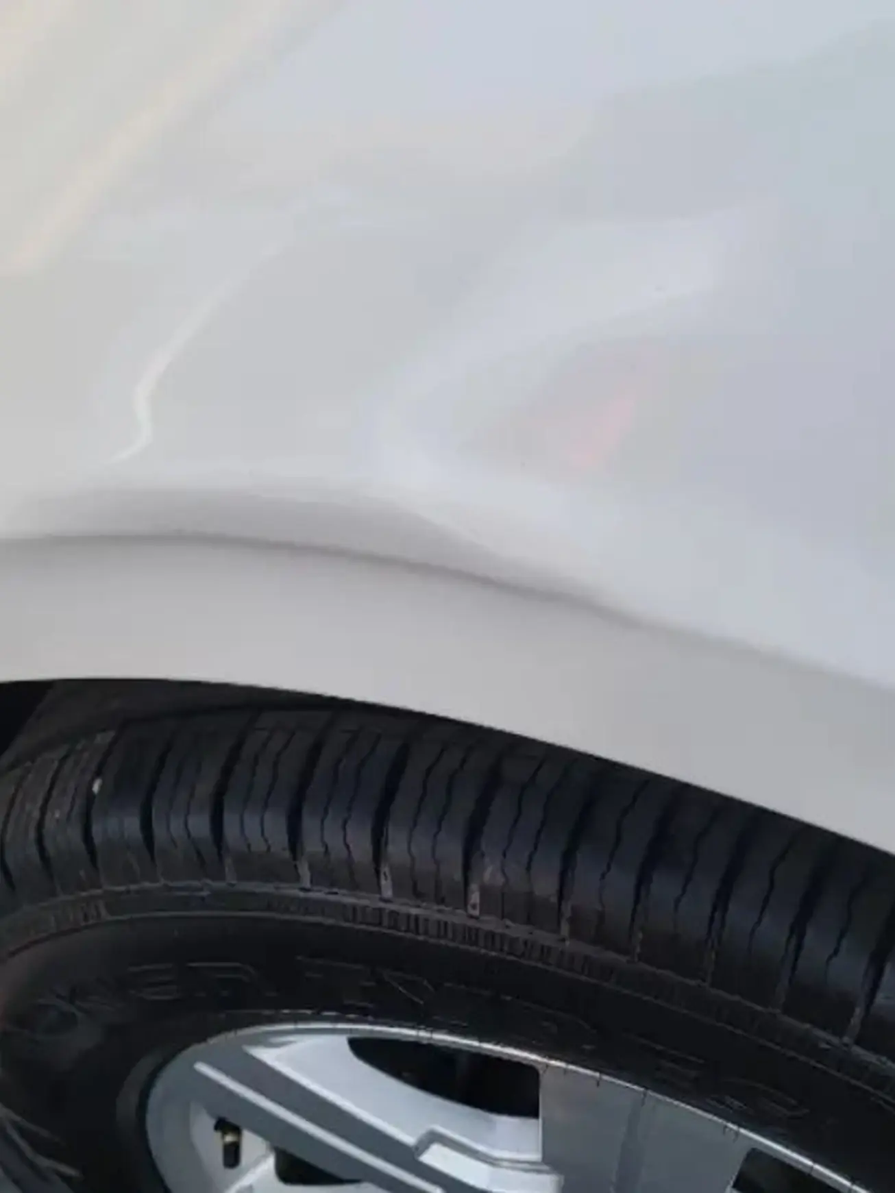Before: Fender dent above the wheel on a white Volkswagen